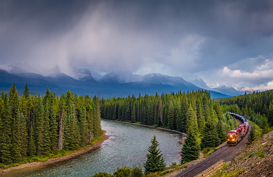 Photo of train tracks along river in Canada