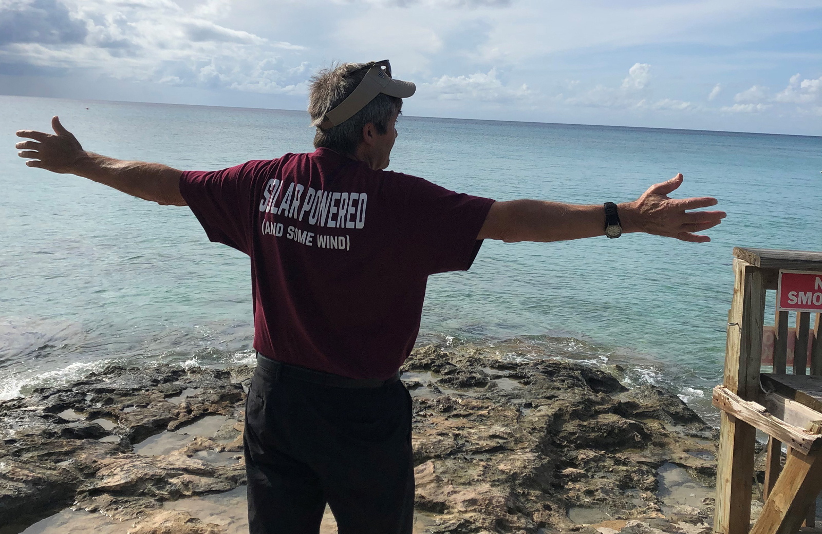 Man standing in front of ocean with arms outstretched