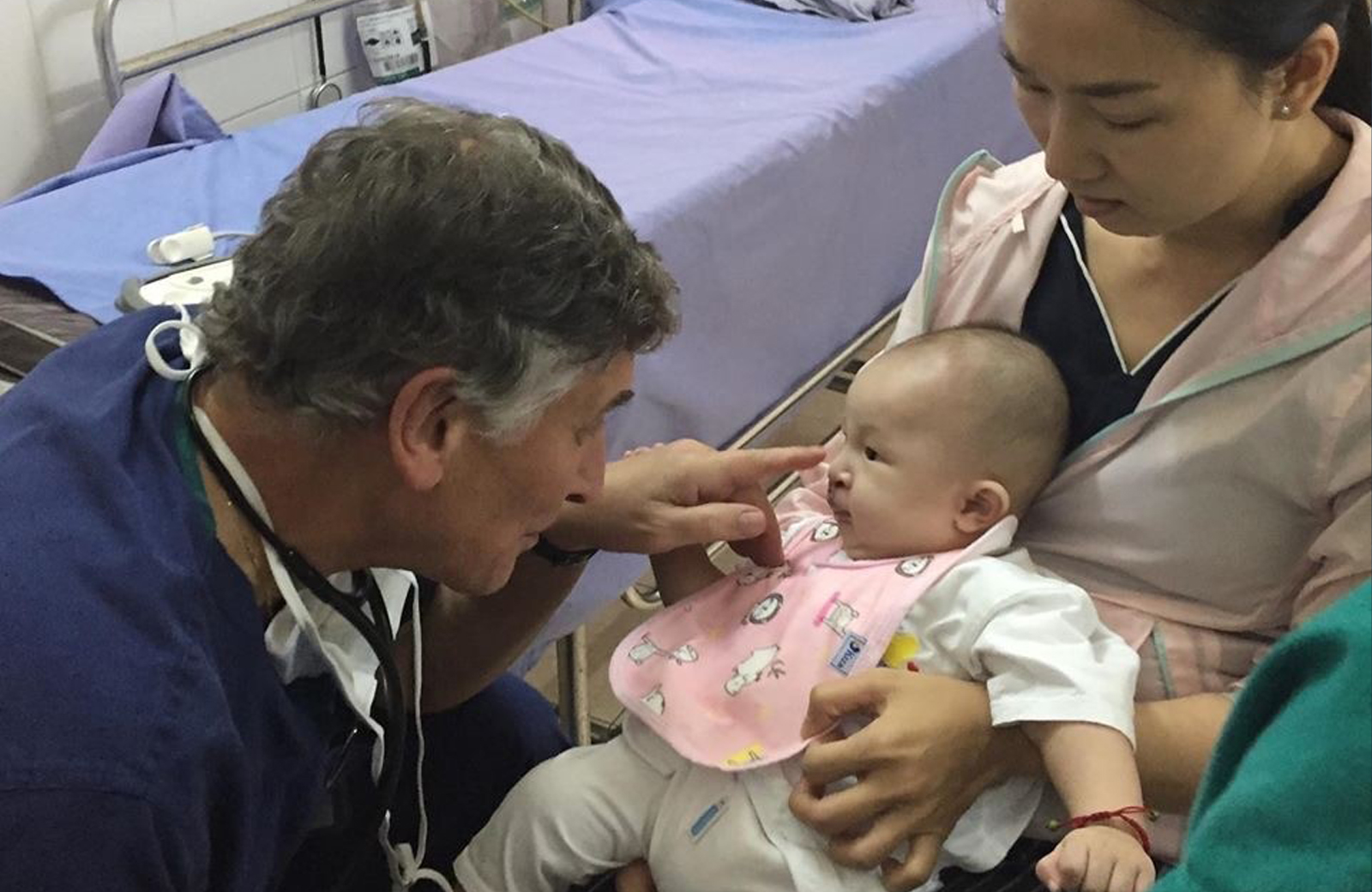 Physician practicing medicine after retirement with woman and baby
