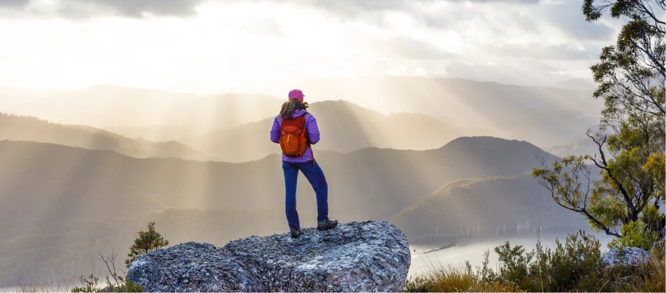 a woman standing on a rock looking out over a valley