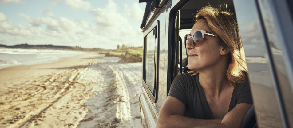 a woman looking out of a car window at the beach